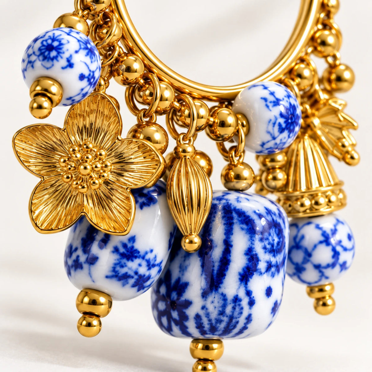 Aro dorado cargado de charms de cerámica azul cobalto y flores en PVD de oro 18K — Alquimia Cobalt, The Wolf Concept